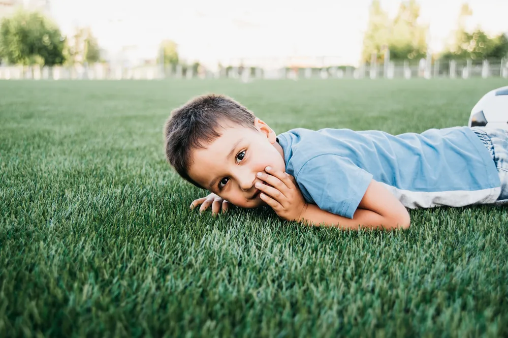 Niños jugando descalzos en pasto sintético anti-calor, seguro para mascotas y familias en Guadalajara